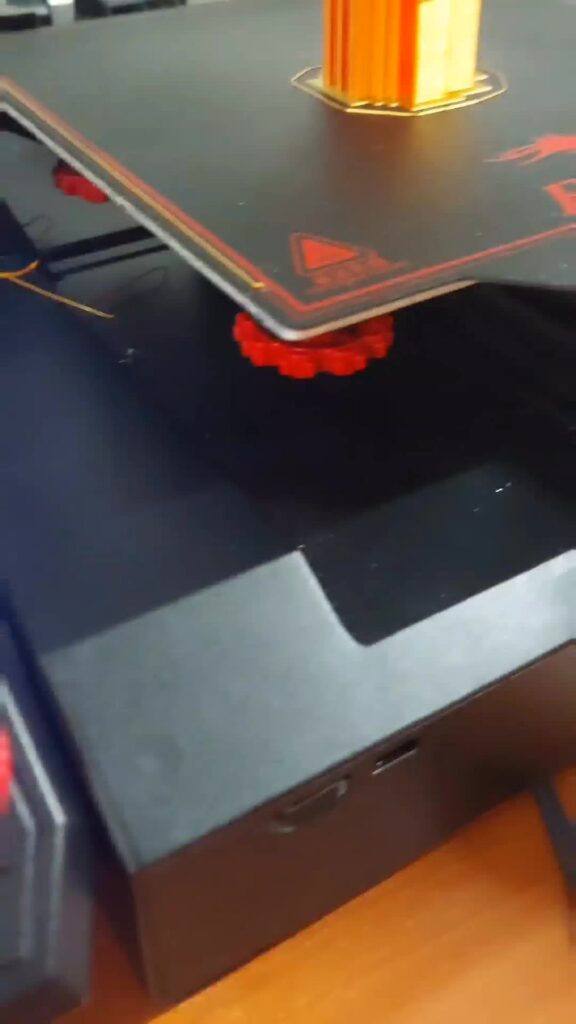 Red leveling knob under one corner of an Ender printer's bed
