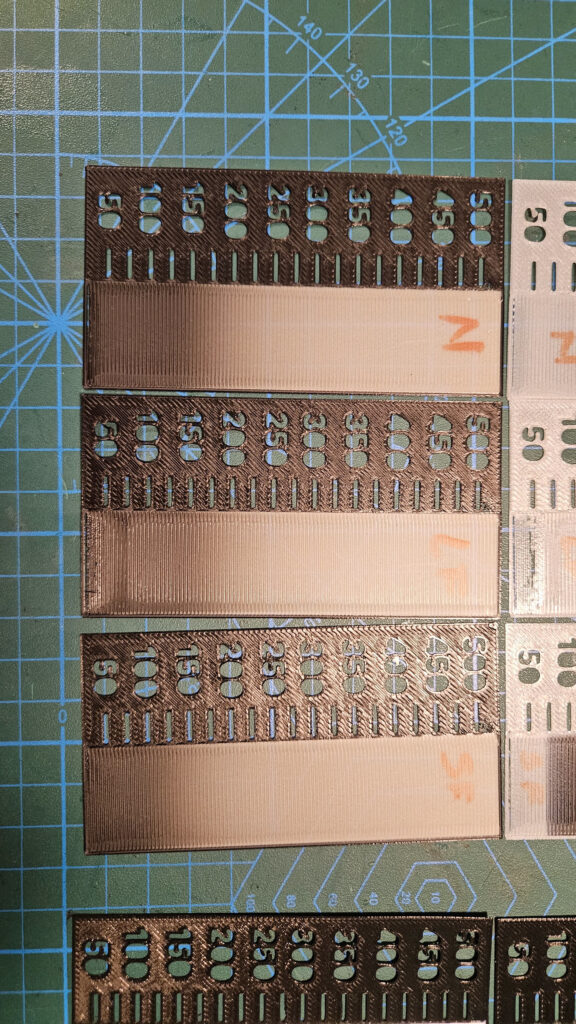 3D Printer Resolution: Why Spec Sheets Mislead and a Simple Test 6 Printed calibration plates with numbered slots and cutouts labelled 50 to 500, in microns