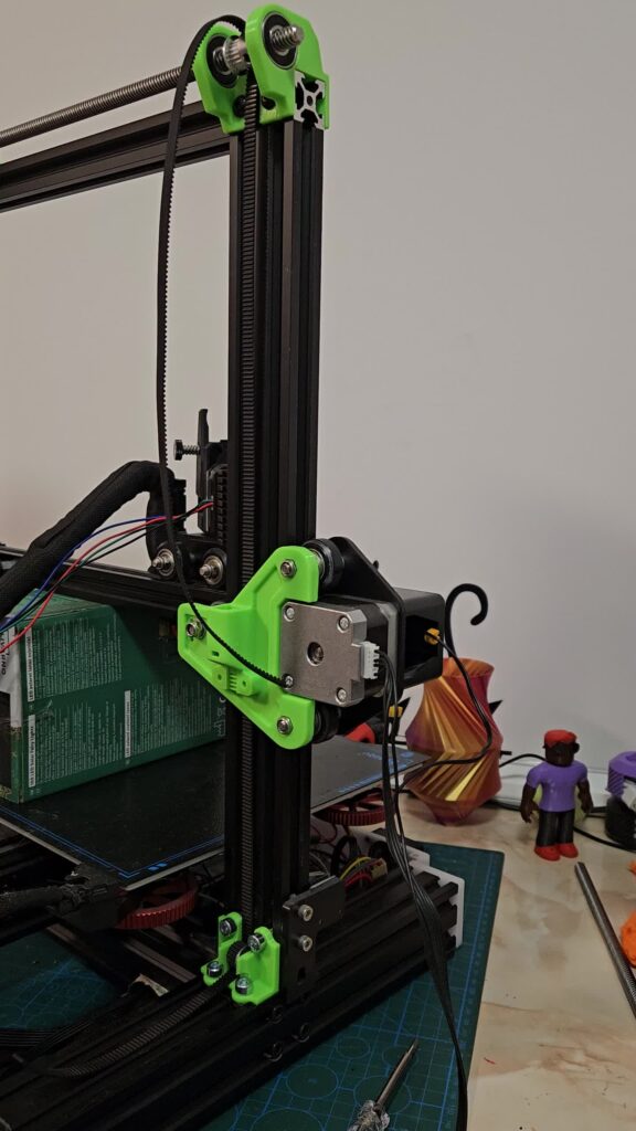 Green printed motor mount holding a stepper motor on a printer Z-axis extrusion, with green printed brackets above and below