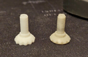 Two 3D printed threaded screws with knurled heads side by side on a dark surface, one new and one showing wear