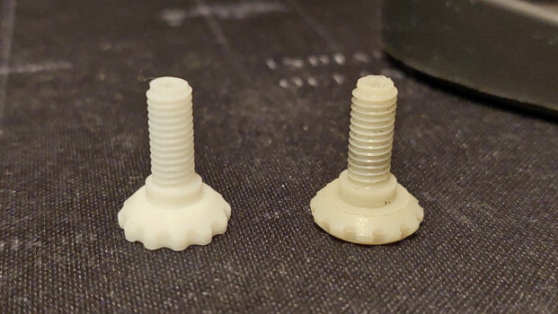 Two 3D printed threaded screws with knurled heads side by side on a dark surface, one new and one showing wear