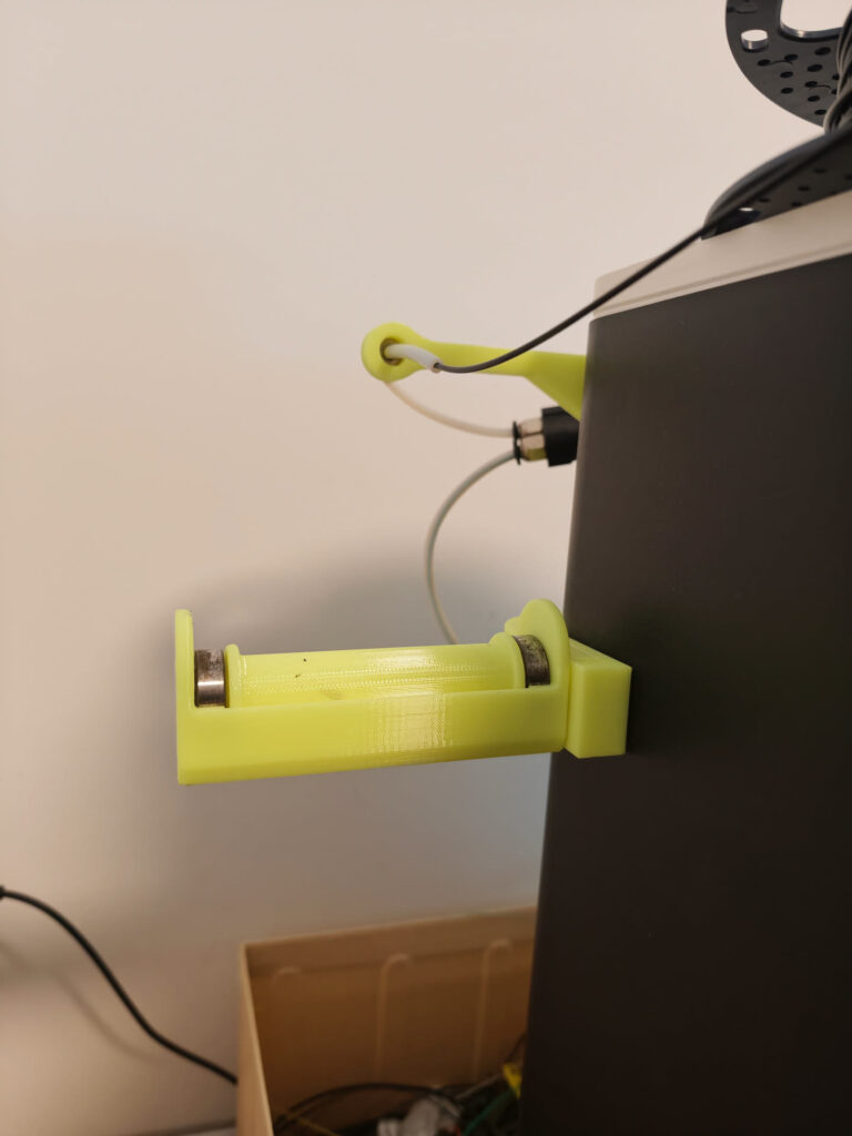 Yellow printed side spool holder with bearings and filament guide arm mounted on the side of a Bambu Lab P1S