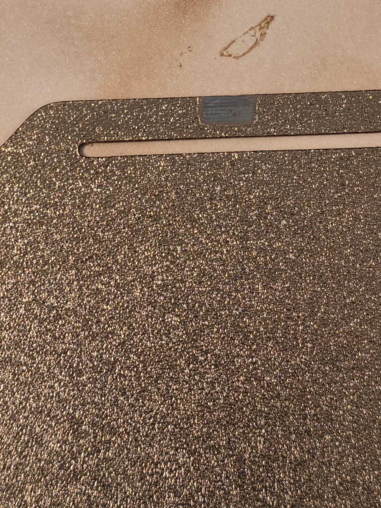 Close-up of the nozzle wipe zone on a Bambu Lab P1S textured PEI plate, where the coating is worn grey beside the slot