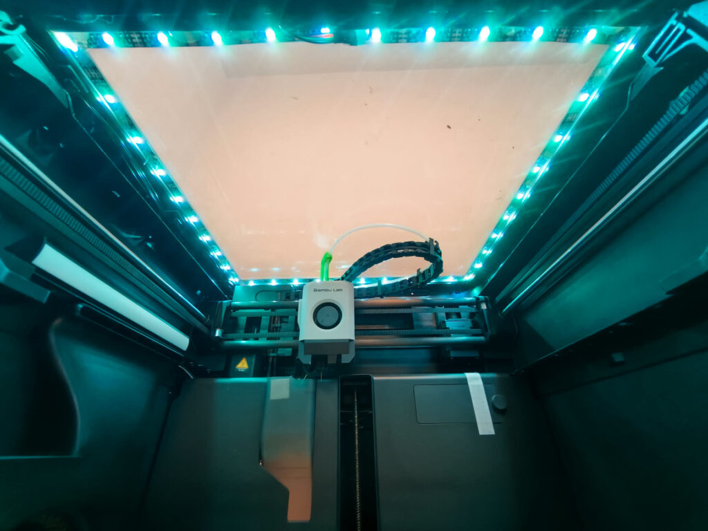 Inside a Bambu Lab P1S looking up at the glass lid, lit by an added LED strip around the top