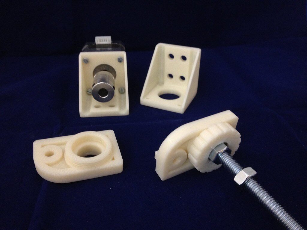 Cream printed motor mount with coupler, bracket, and threaded-rod bearing blocks on blue cloth.